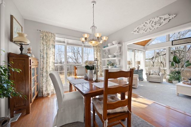 dining area with wood finished floors, a healthy amount of sunlight, and a chandelier