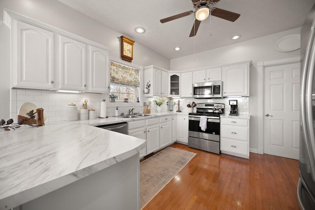 kitchen with a sink, light wood-style floors, white cabinetry, and stainless steel appliances