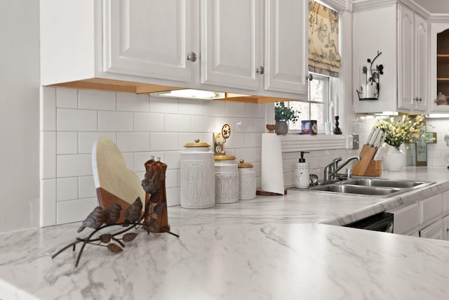 kitchen featuring a sink, glass insert cabinets, backsplash, and white cabinets