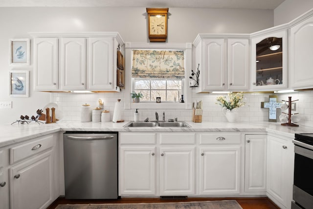 kitchen with backsplash, glass insert cabinets, stainless steel appliances, white cabinetry, and a sink