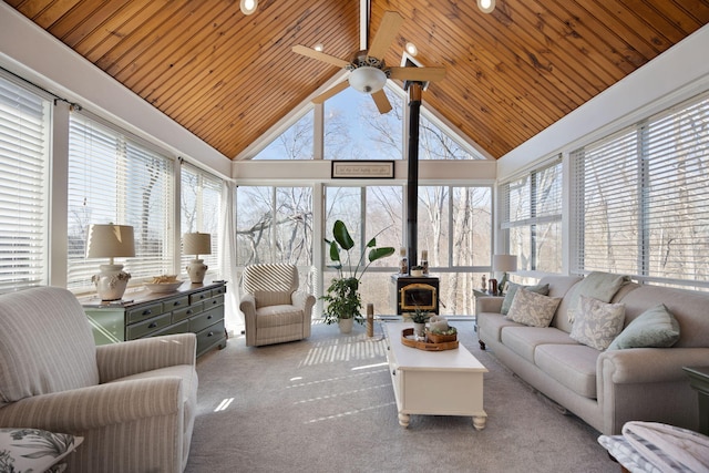 carpeted living area with high vaulted ceiling, wood ceiling, ceiling fan, and a wood stove