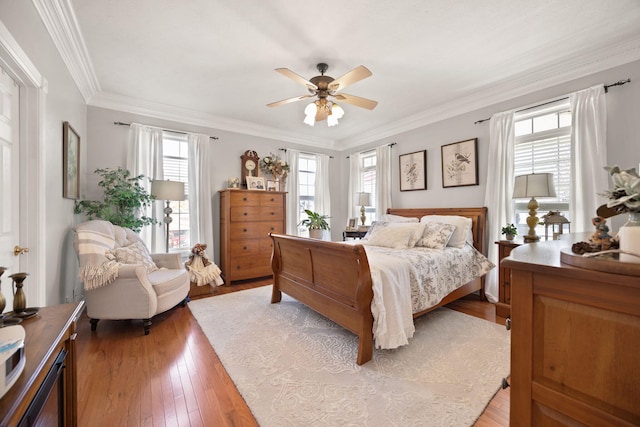 bedroom featuring light wood-type flooring, ornamental molding, and a ceiling fan