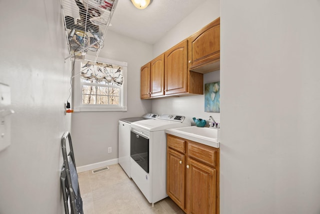 clothes washing area with washing machine and clothes dryer, visible vents, baseboards, cabinet space, and a sink