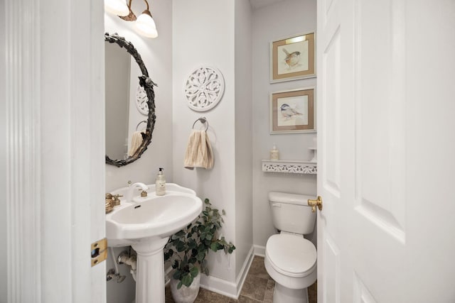 bathroom with toilet, baseboards, and a sink