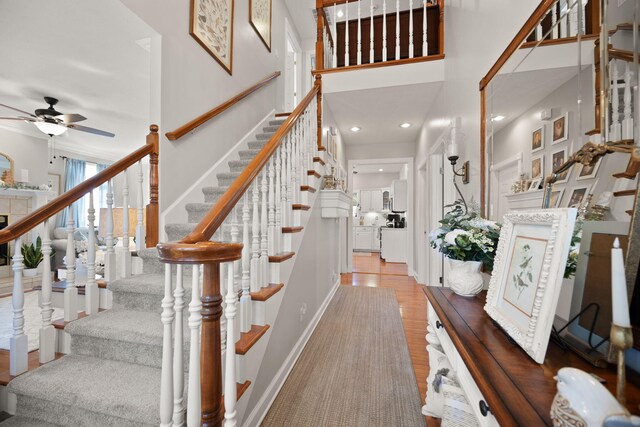 interior space with stairway, ceiling fan, a towering ceiling, and wood finished floors