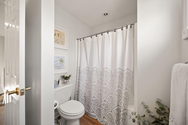 bathroom featuring toilet, a shower with curtain, and wood finished floors