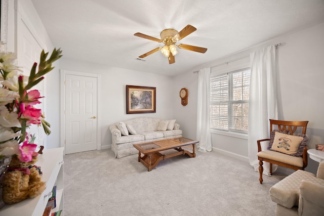 living area with visible vents, baseboards, carpet, and a ceiling fan