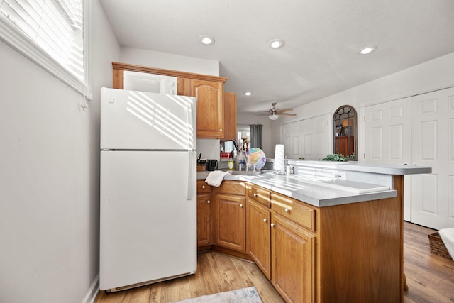 kitchen featuring recessed lighting, light wood finished floors, a peninsula, and freestanding refrigerator