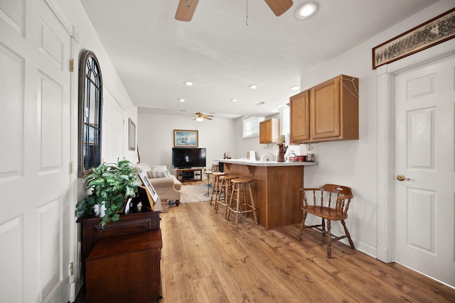 living area featuring baseboards, recessed lighting, light wood-type flooring, and ceiling fan