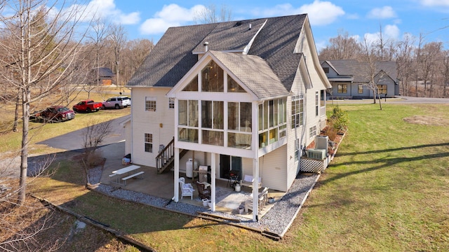 rear view of house with a patio area, a lawn, roof with shingles, and a sunroom