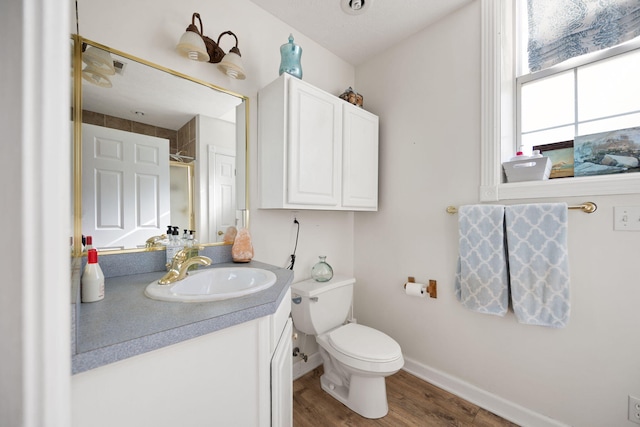 bathroom with vanity, toilet, wood finished floors, and baseboards