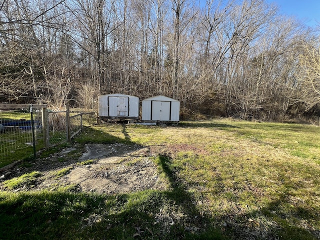 view of yard featuring an outbuilding, a storage shed, and fence