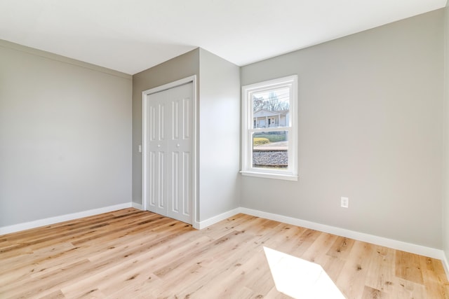 unfurnished bedroom featuring a closet, baseboards, and wood finished floors