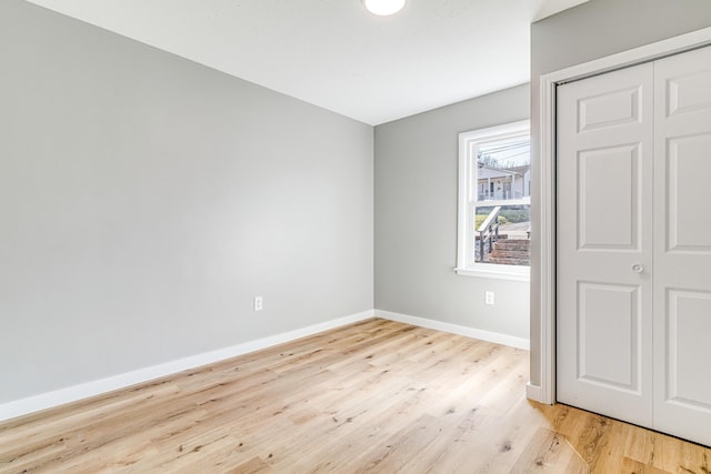 unfurnished bedroom with light wood finished floors, a closet, and baseboards