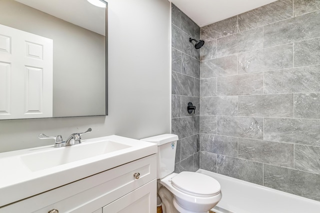 bathroom featuring toilet, tiled shower, and vanity