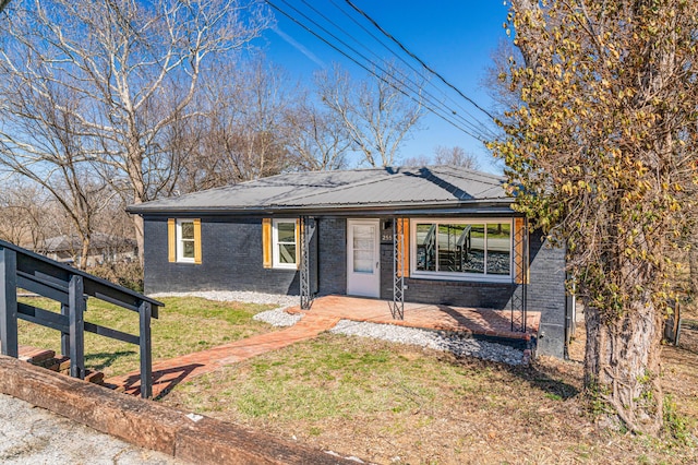 view of front of house with a front lawn, a porch, brick siding, and metal roof