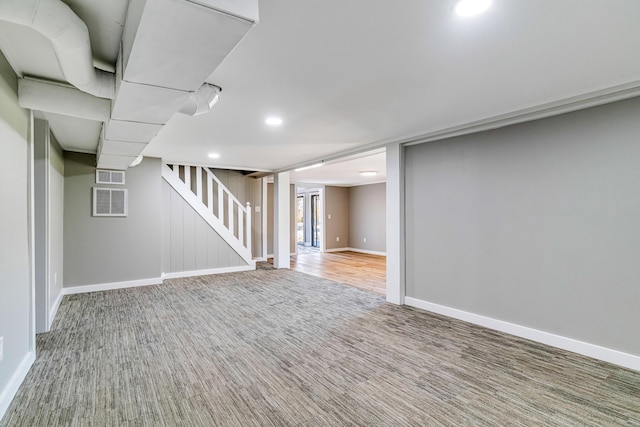 finished below grade area featuring carpet flooring, baseboards, visible vents, and stairs