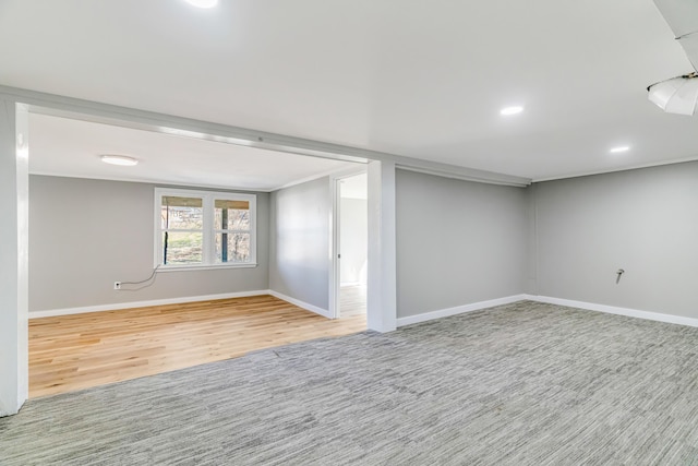 basement featuring recessed lighting, ornamental molding, baseboards, and wood finished floors