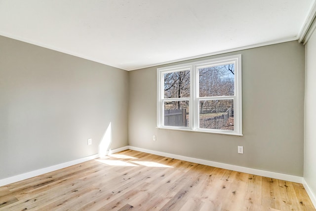 empty room featuring crown molding, wood finished floors, and baseboards