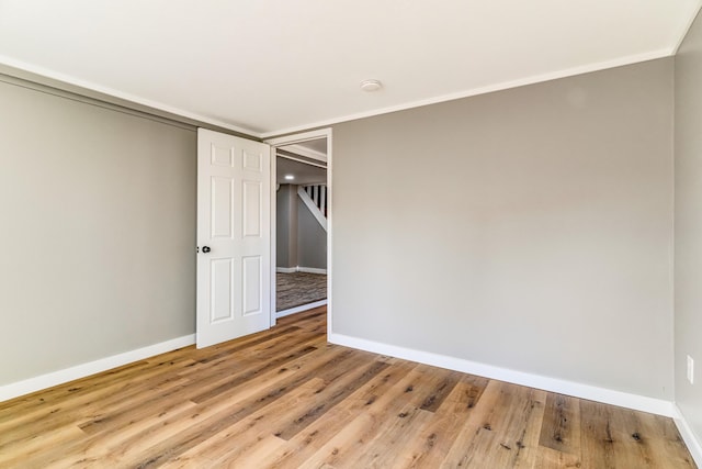 empty room featuring ornamental molding, baseboards, and wood finished floors