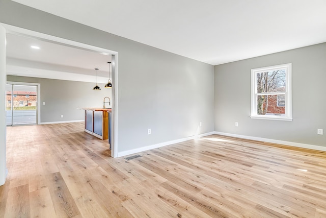 spare room featuring visible vents, baseboards, recessed lighting, a sink, and light wood-style floors