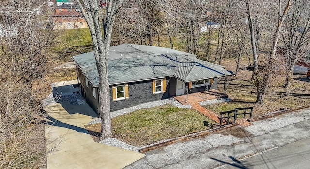 view of front facade featuring stone siding, metal roof, and a front yard