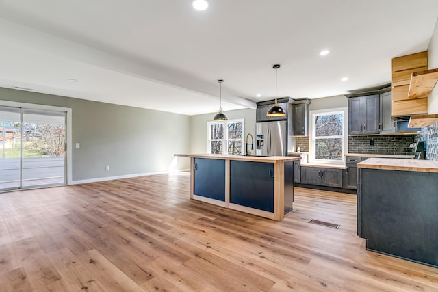 kitchen featuring baseboards, light wood-style flooring, butcher block countertops, decorative backsplash, and stainless steel refrigerator with ice dispenser