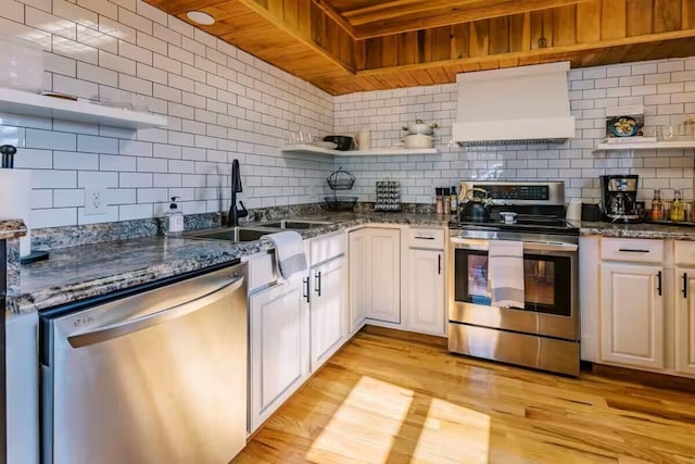 kitchen featuring open shelves, custom range hood, tasteful backsplash, and appliances with stainless steel finishes