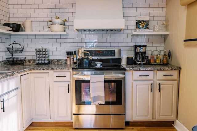 kitchen with tasteful backsplash, electric stove, custom range hood, and open shelves