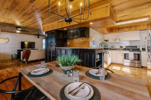 dining area featuring a wainscoted wall, light wood-style floors, wood ceiling, and ceiling fan