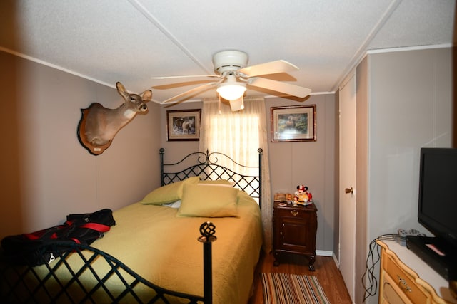 bedroom with dark wood-type flooring, ornamental molding, and a ceiling fan