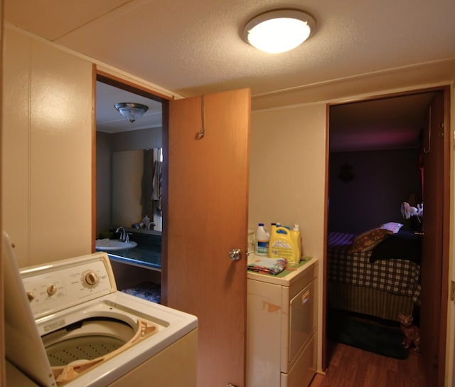 laundry area featuring a sink, a textured ceiling, washer / dryer, and wood finished floors