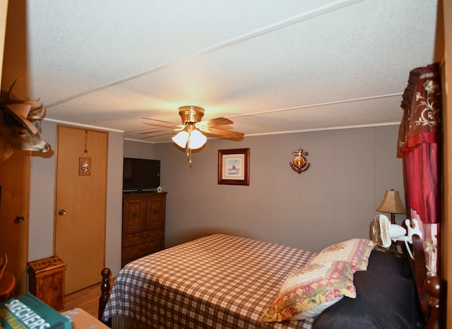 bedroom featuring crown molding, ceiling fan, and wood finished floors