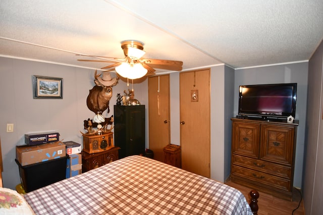 bedroom featuring ornamental molding, a textured ceiling, a ceiling fan, and wood finished floors