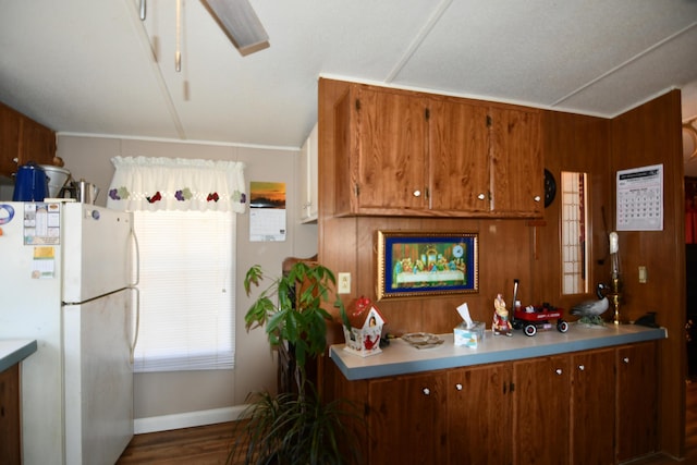 kitchen with baseboards, light countertops, brown cabinets, freestanding refrigerator, and wood finished floors