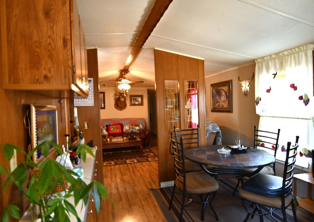 dining room with a ceiling fan, beam ceiling, and wood finished floors