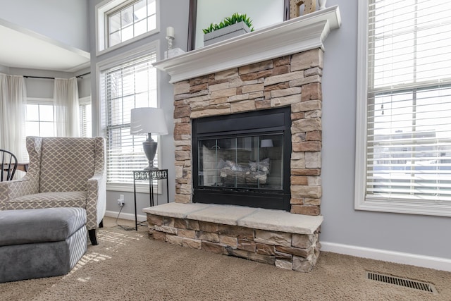 carpeted living area featuring visible vents, a fireplace, and baseboards