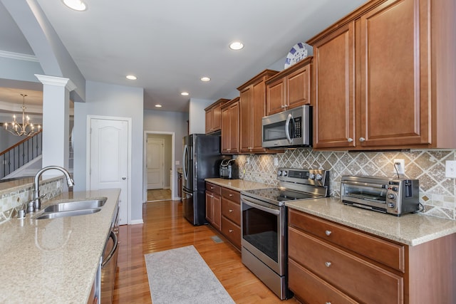 kitchen featuring brown cabinetry, light wood-style flooring, a toaster, a sink, and appliances with stainless steel finishes