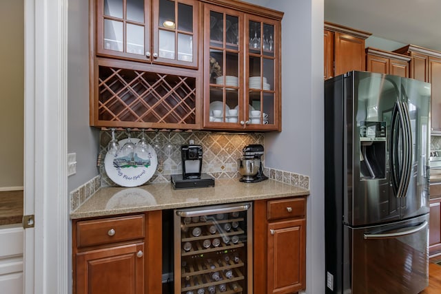 bar with a dry bar, wine cooler, backsplash, and black fridge