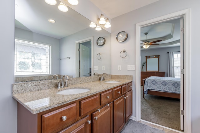 ensuite bathroom with double vanity, connected bathroom, ceiling fan, and a sink