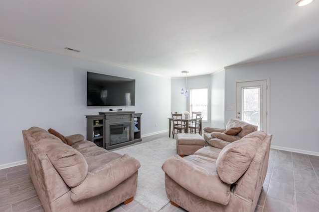 living area with visible vents, baseboards, and ornamental molding