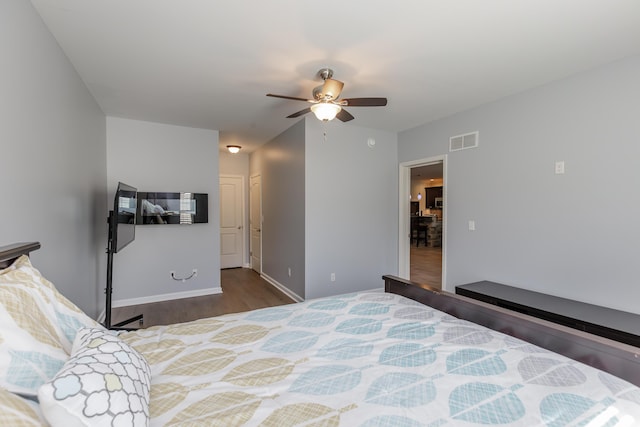 bedroom with visible vents, baseboards, wood finished floors, and a ceiling fan