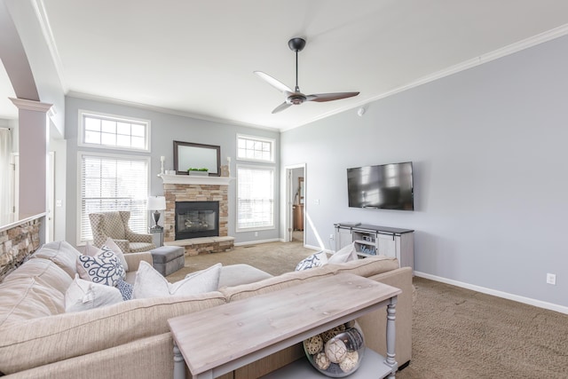 living area featuring light carpet, a ceiling fan, a stone fireplace, crown molding, and baseboards