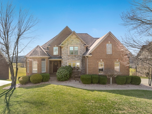 view of front of property featuring a front yard, brick siding, and stone siding