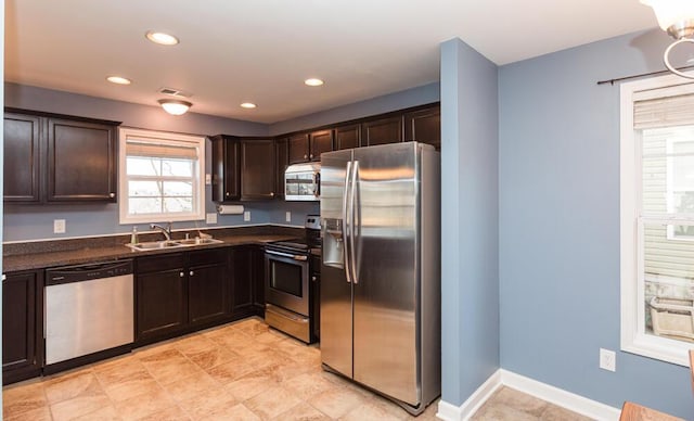 kitchen with recessed lighting, a sink, dark brown cabinetry, appliances with stainless steel finishes, and dark countertops