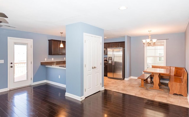 kitchen with dark brown cabinets, wood finished floors, and stainless steel refrigerator with ice dispenser