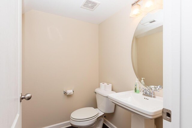 bathroom with visible vents, toilet, baseboards, and a sink