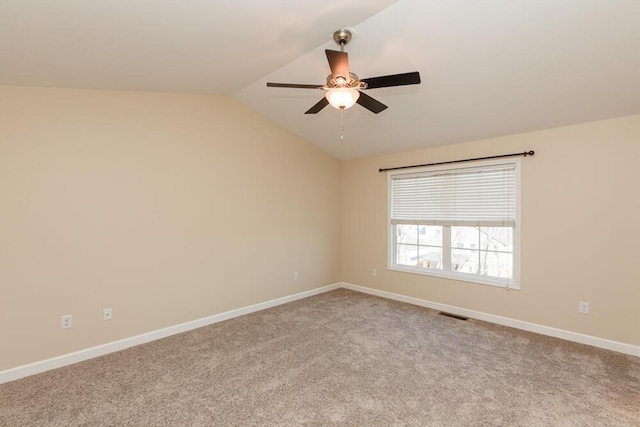 carpeted spare room featuring baseboards, lofted ceiling, visible vents, and a ceiling fan