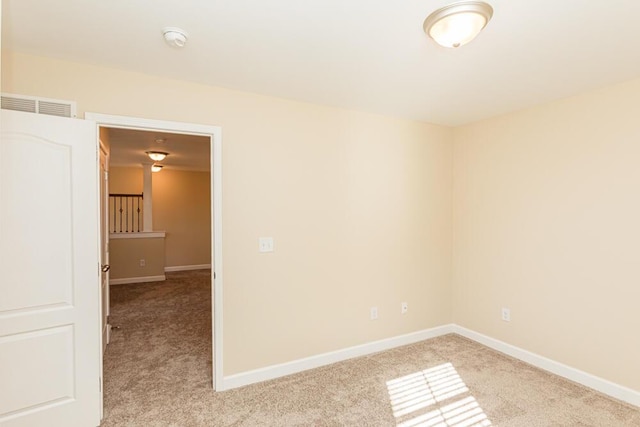 empty room with visible vents, light carpet, and baseboards