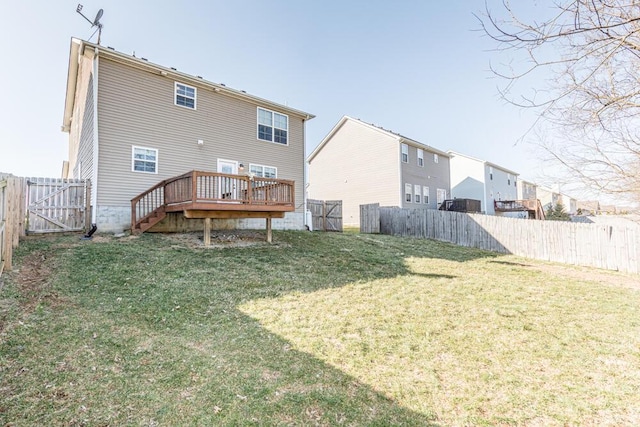 back of house featuring a fenced backyard, a lawn, a deck, and a gate